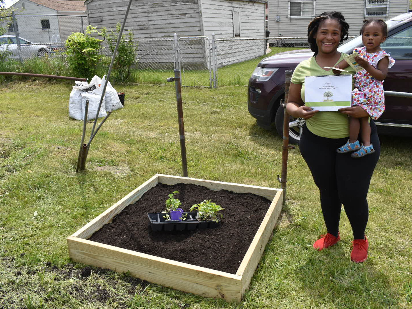 Detroit family beside the raised bed Peace Tree Parks installed at their home