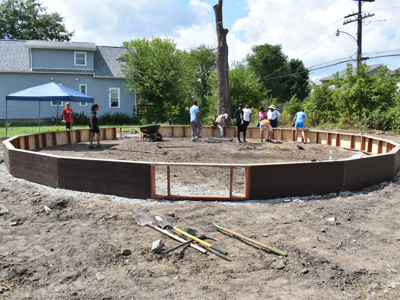 Neighbors framing out the base of a new garden bed beside the greenhouse