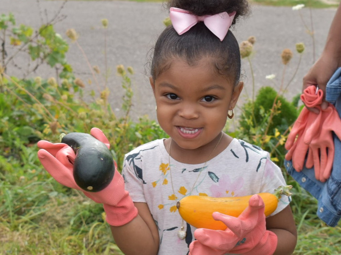 Young child holding vegetables picked at the community garden